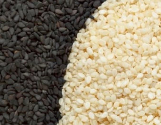 Contrasting piles of black and white sesame seeds meeting in a gentle, vertical curve.